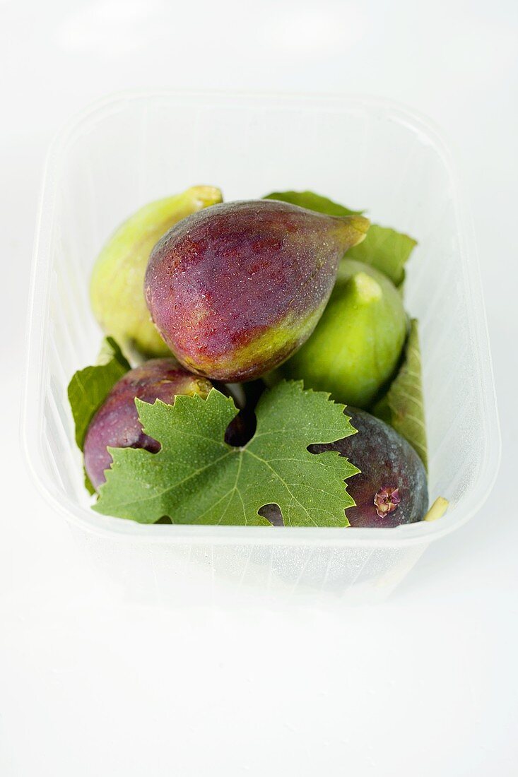 Several figs with leaf in plastic punnet