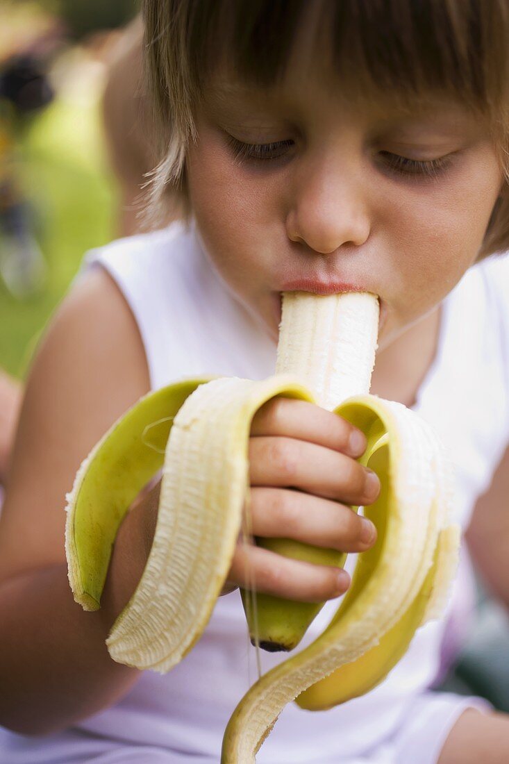 Small child biting into a banana