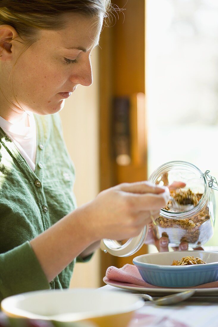 Junge Frau bereitet sich Müsli vor