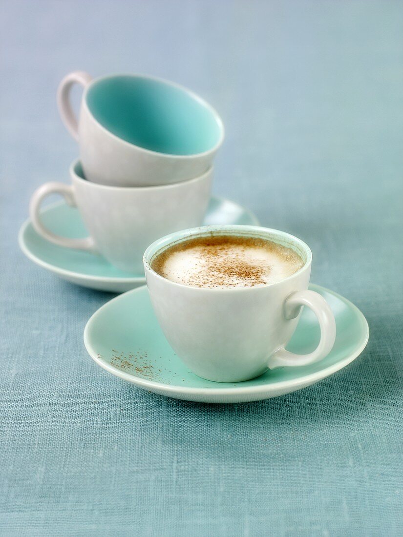 Ein Tasse Cappuccino und zwei leere Tassen