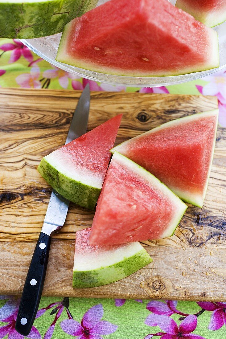 Melonenschnitze und Messer auf einem Holzbrett