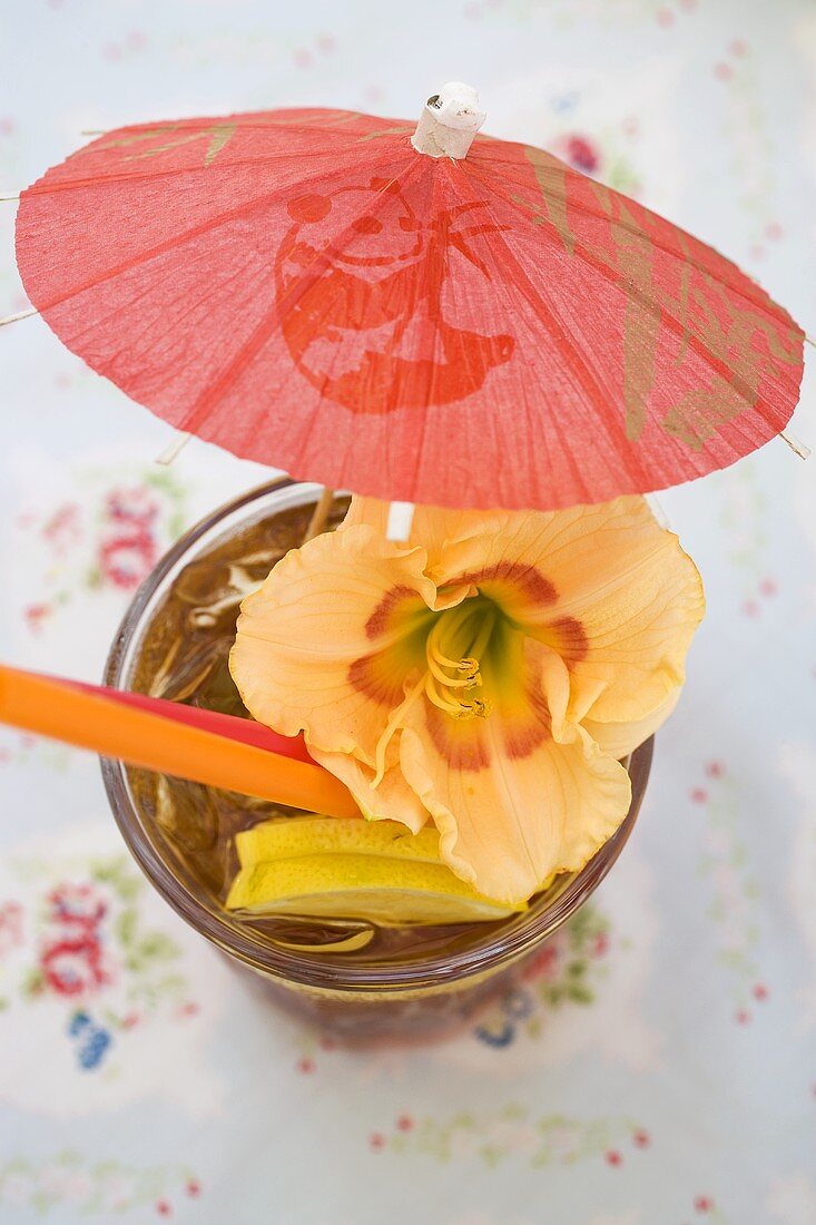 Cuba Libre mit Schirmchen und Amaryllis-Blüte