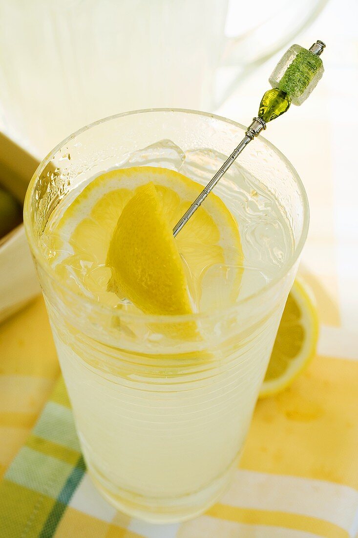 A glass of lemonade with lemon wedge on cocktail stick