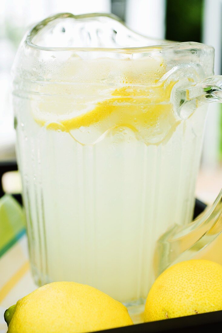 Lemonade in a glass jug with slices of lemon