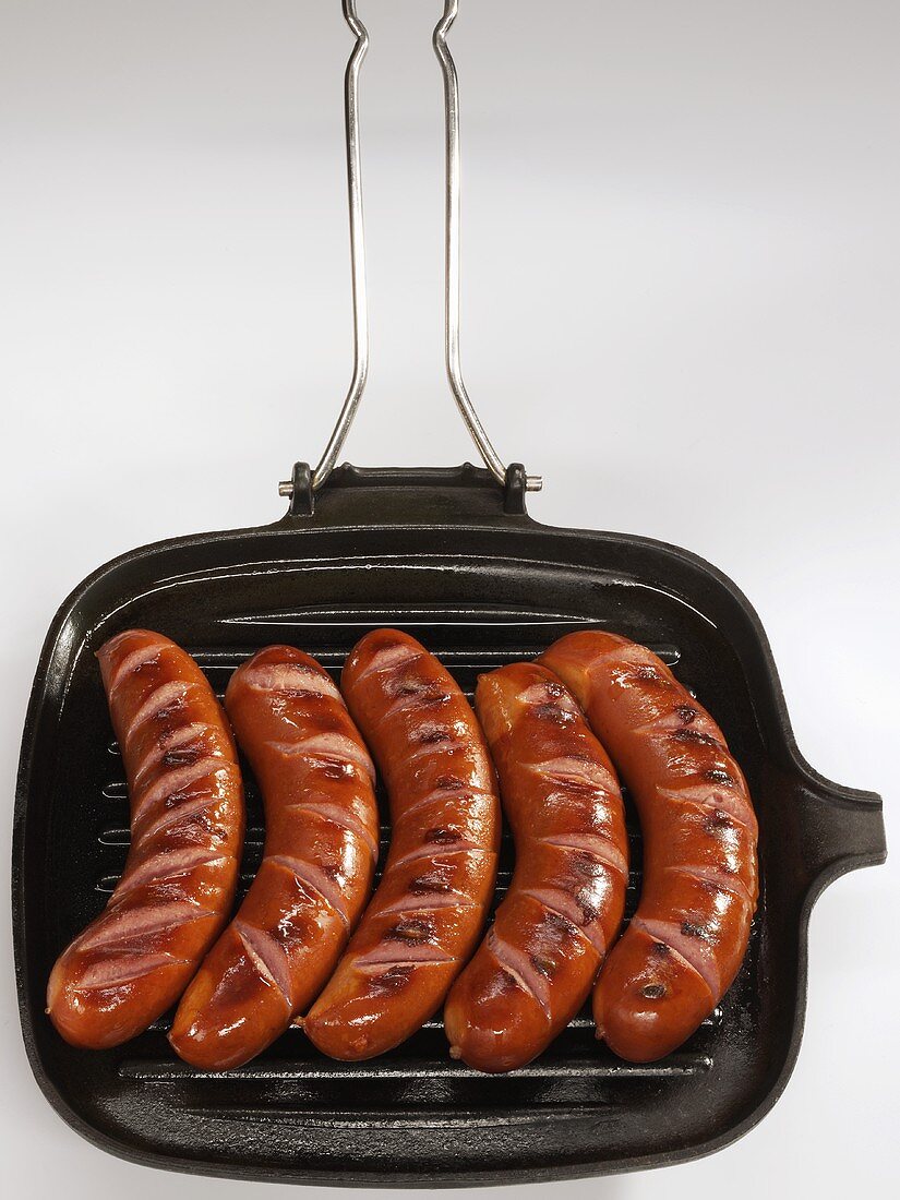 Five bockwurst sausages in a grill pan