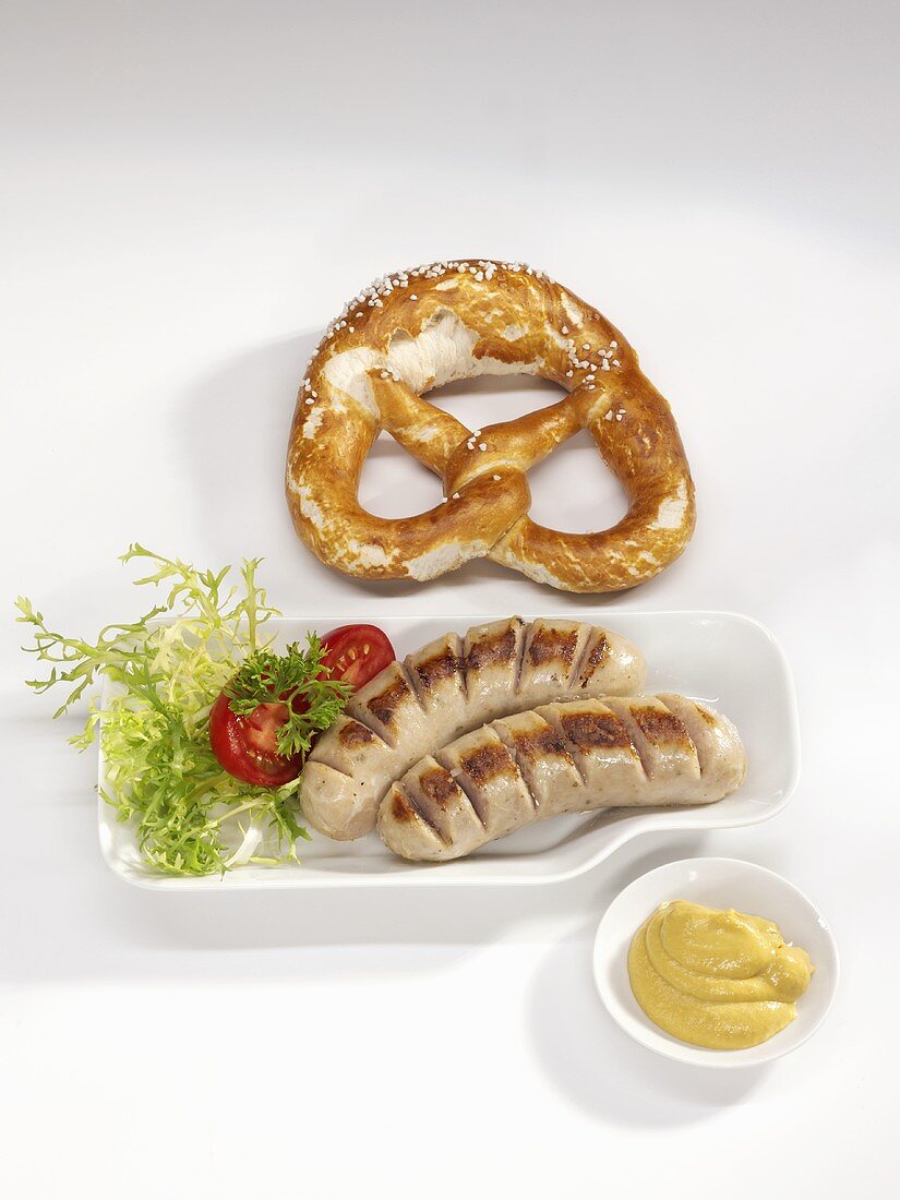 Two fried sausages with mustard and pretzel