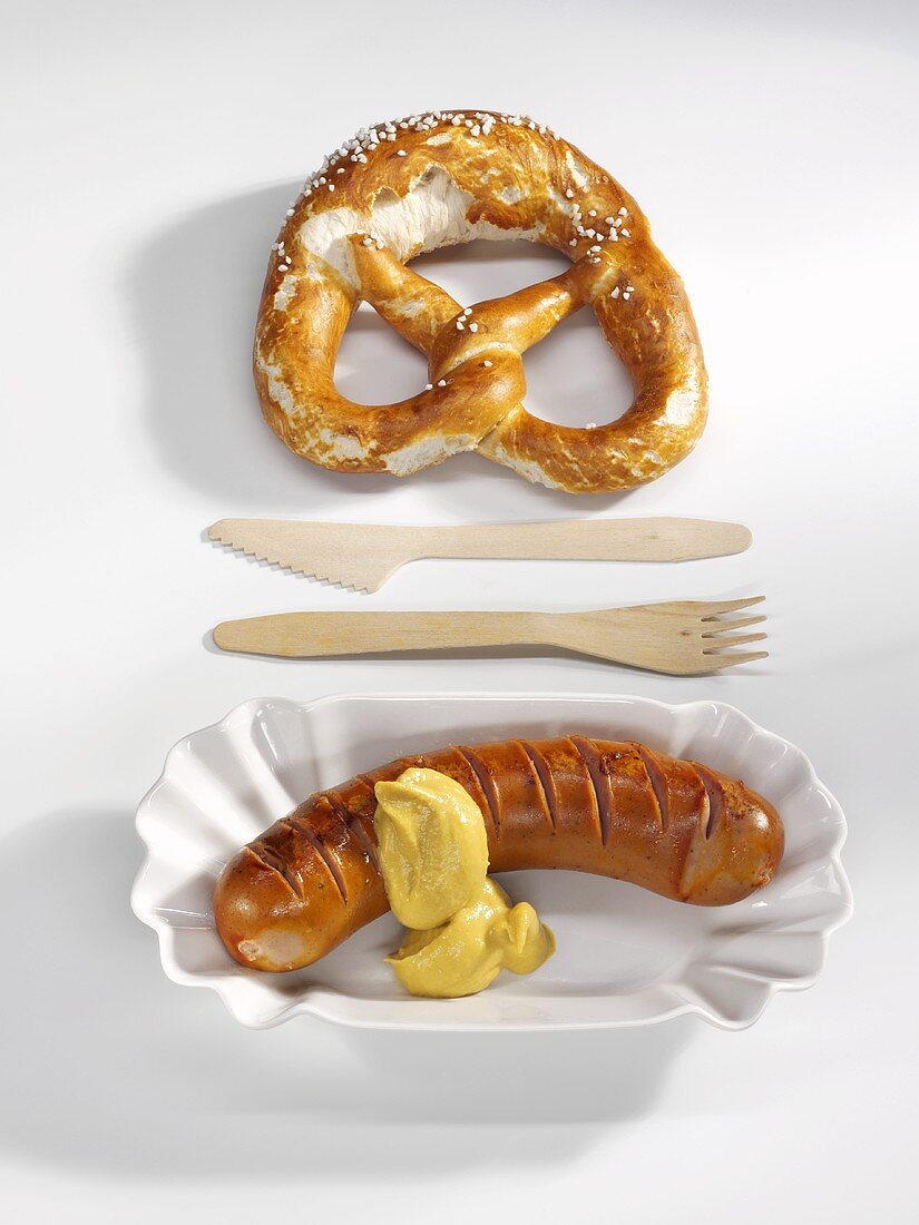 Red sausage with mustard and pretzel