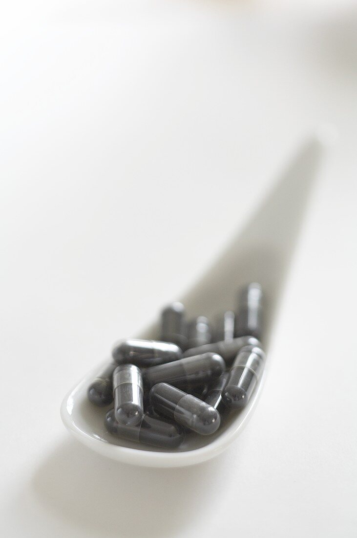 Charcoal capsules on a porcelain spoon