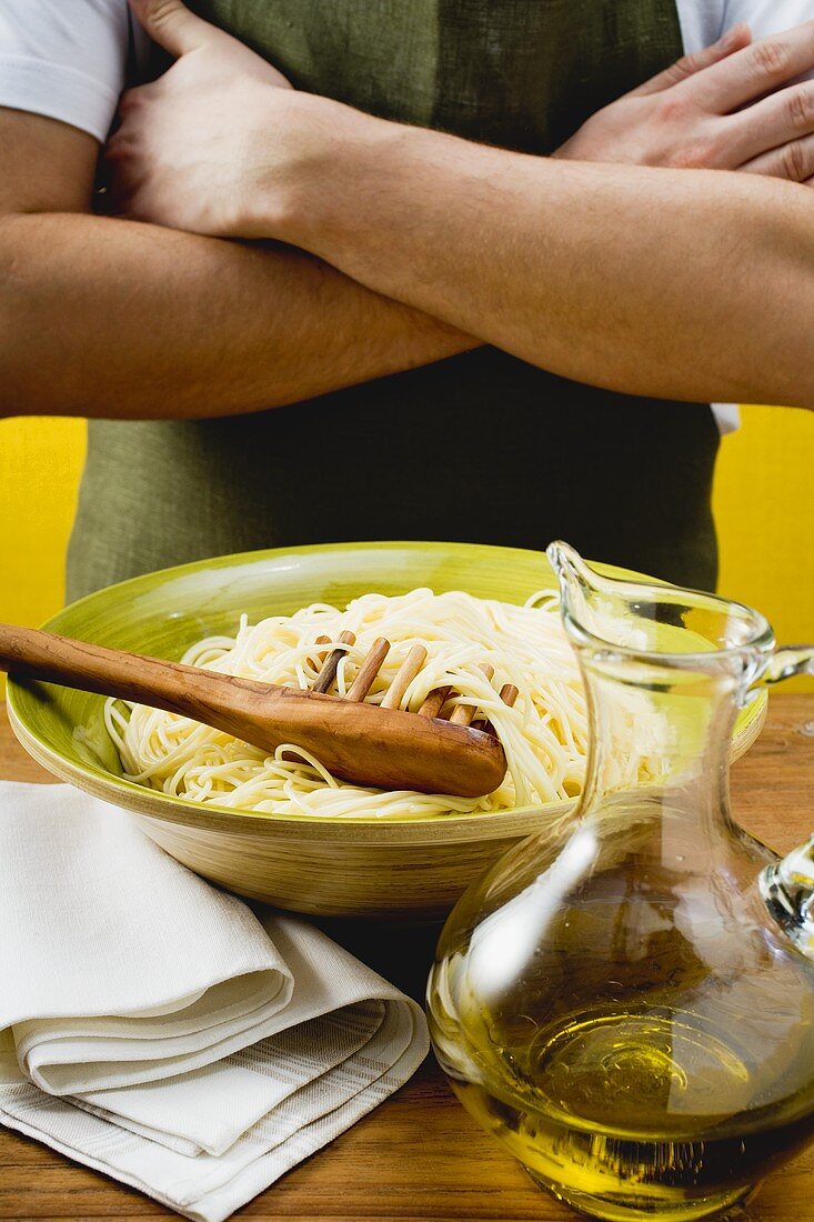 A dish of spaghetti with spaghetti server and olive oil