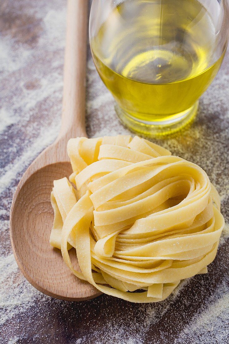 Home-made ribbon pasta with wooden spoon and olive oil