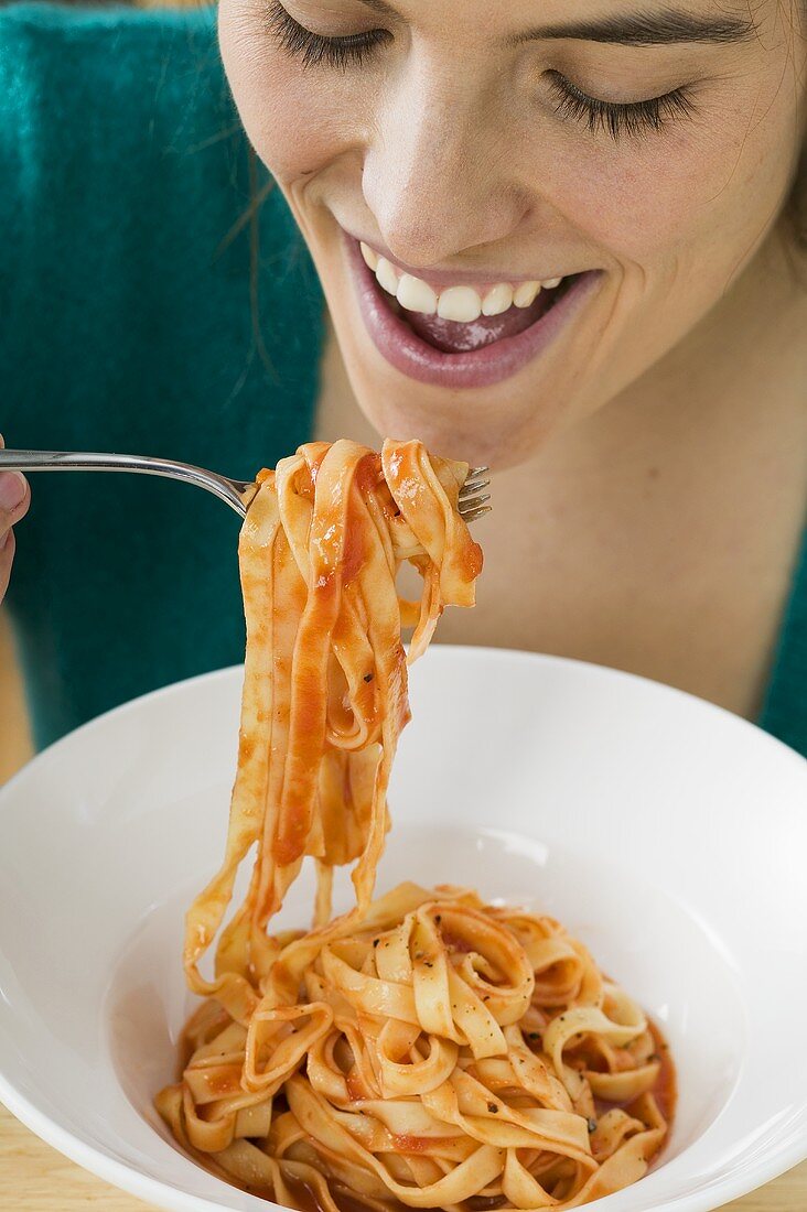 Frau isst Bandnudeln mit Tomatensauce