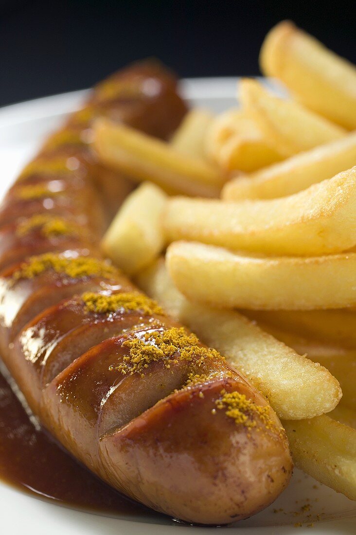 Currywurst with ketchup, curry powder and chips on a plate