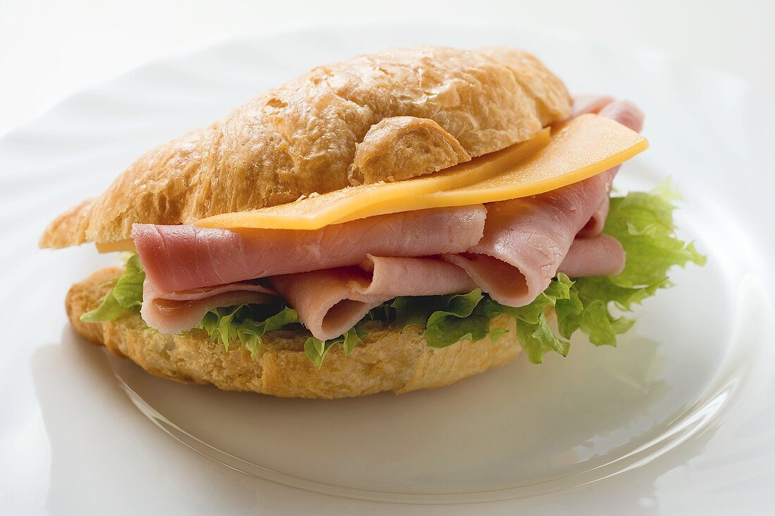 Croissant filled with ham and cheese on plate