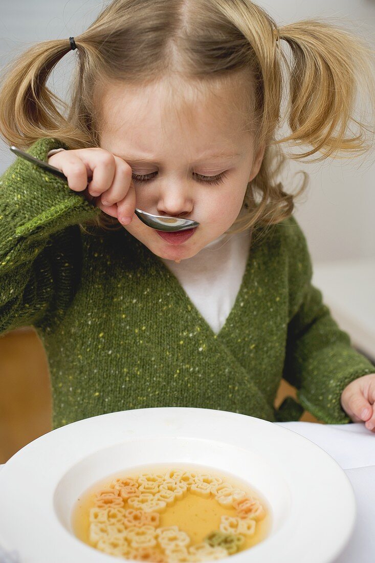 Kleines Mädchen isst Bärchen-Nudel-Suppe
