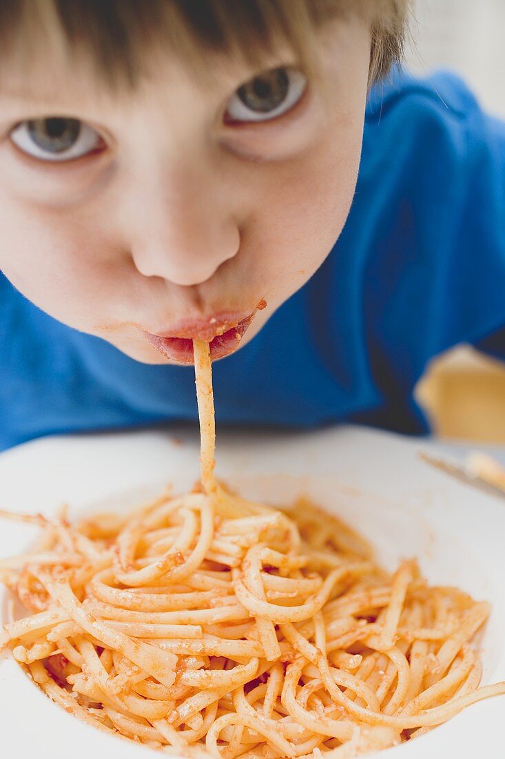 Small boy eating spaghetti
