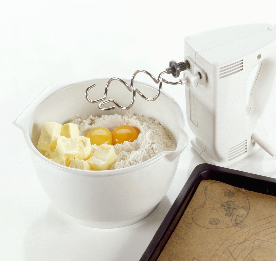 Flour, butter and eggs in a bowl with mixer