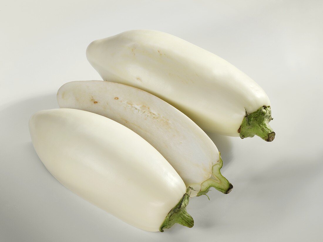 Two white aubergines, one halved