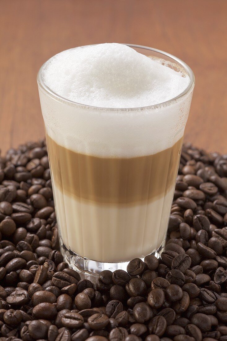 A glass of latte macchiato on a heap of coffee beans