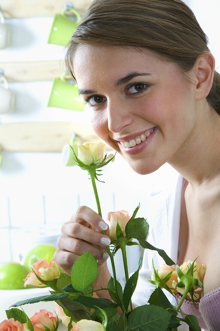 Junge Frau riecht an einer Rosenblüte