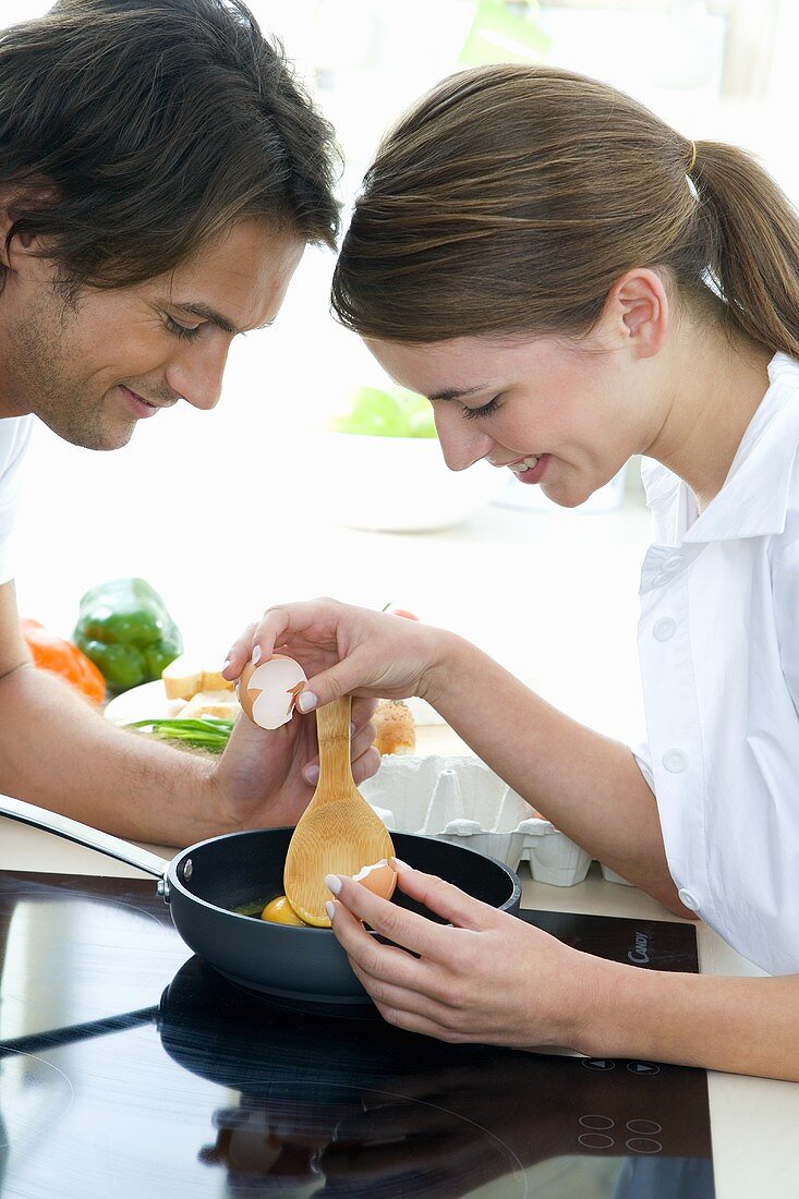 Young couple making scrambled eggs