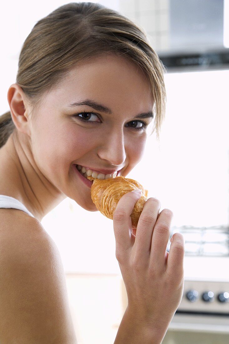 Young woman biting into a croissant
