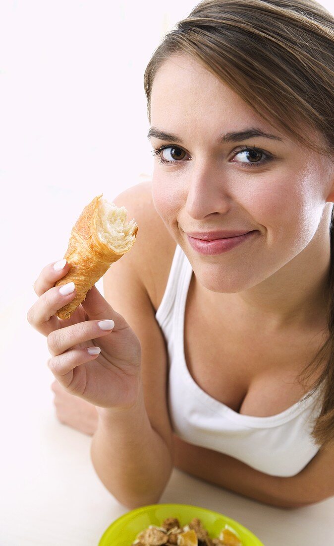Junge Frau hält angebissenes Croissant in der Hand