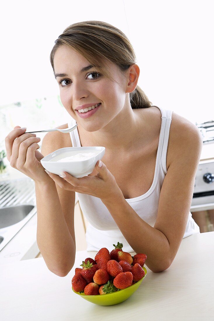 Young woman eating yoghurt out of a small bowl