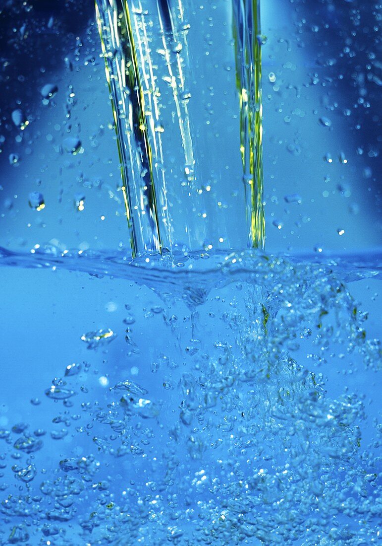 Ein Wasserstrahl fällt ins Wasser und erzeugt Luftblasen