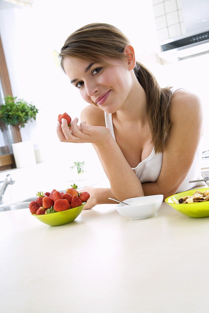 Young woman holding a strawberry with a bite taken