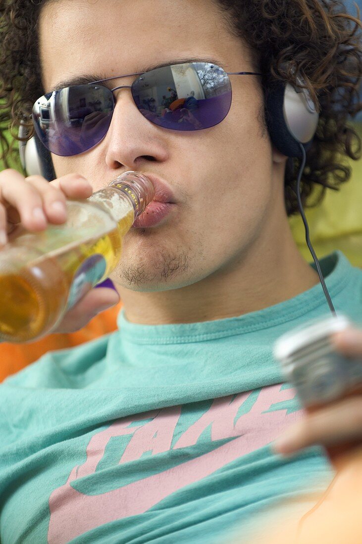 Jugendlicher trinkt Bier und hört Musik