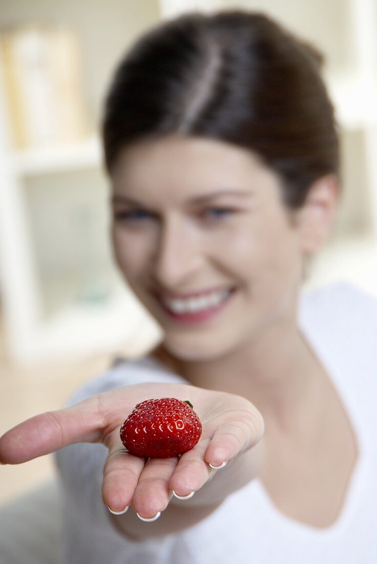 Woman holding a strawberry on her outstretched hand