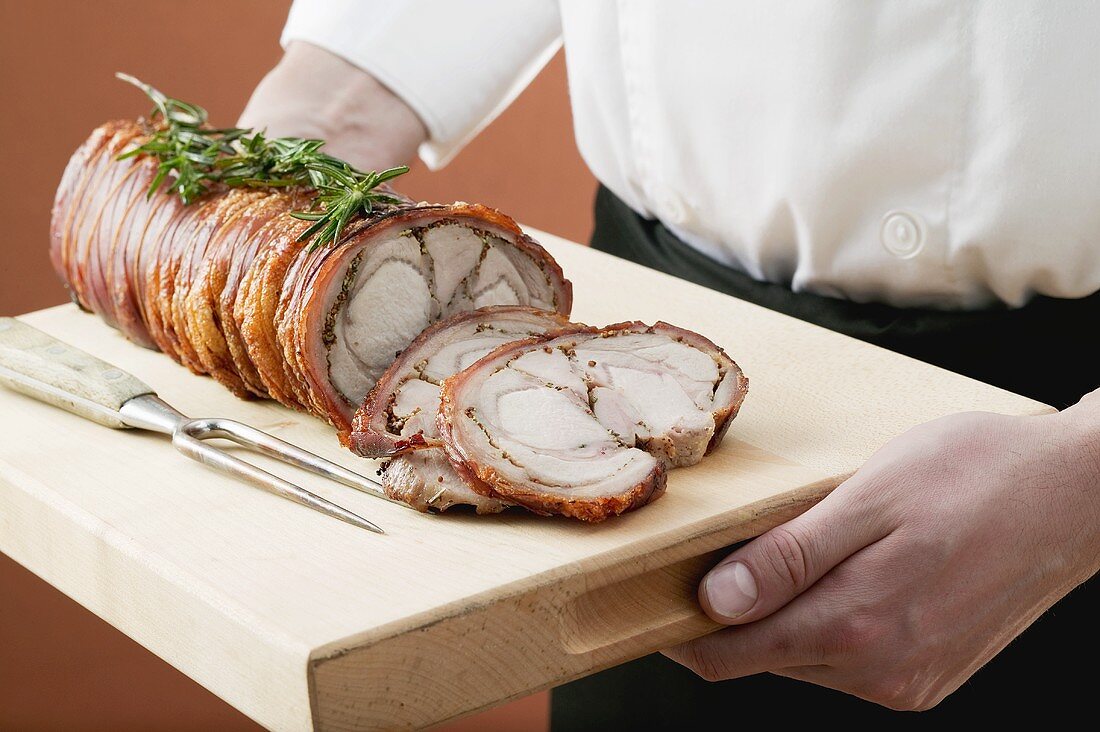 Rolled saddle of suckling pig on a wooden board