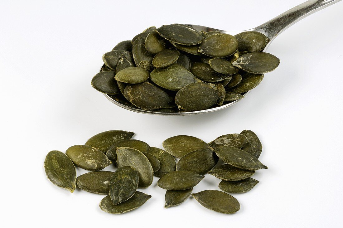 Pumpkin seeds on and beside a spoon