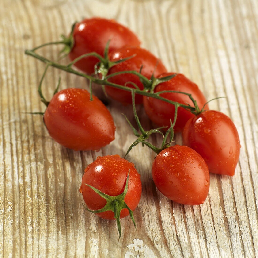 Eiertomaten an der Rispe auf Holzuntergrund