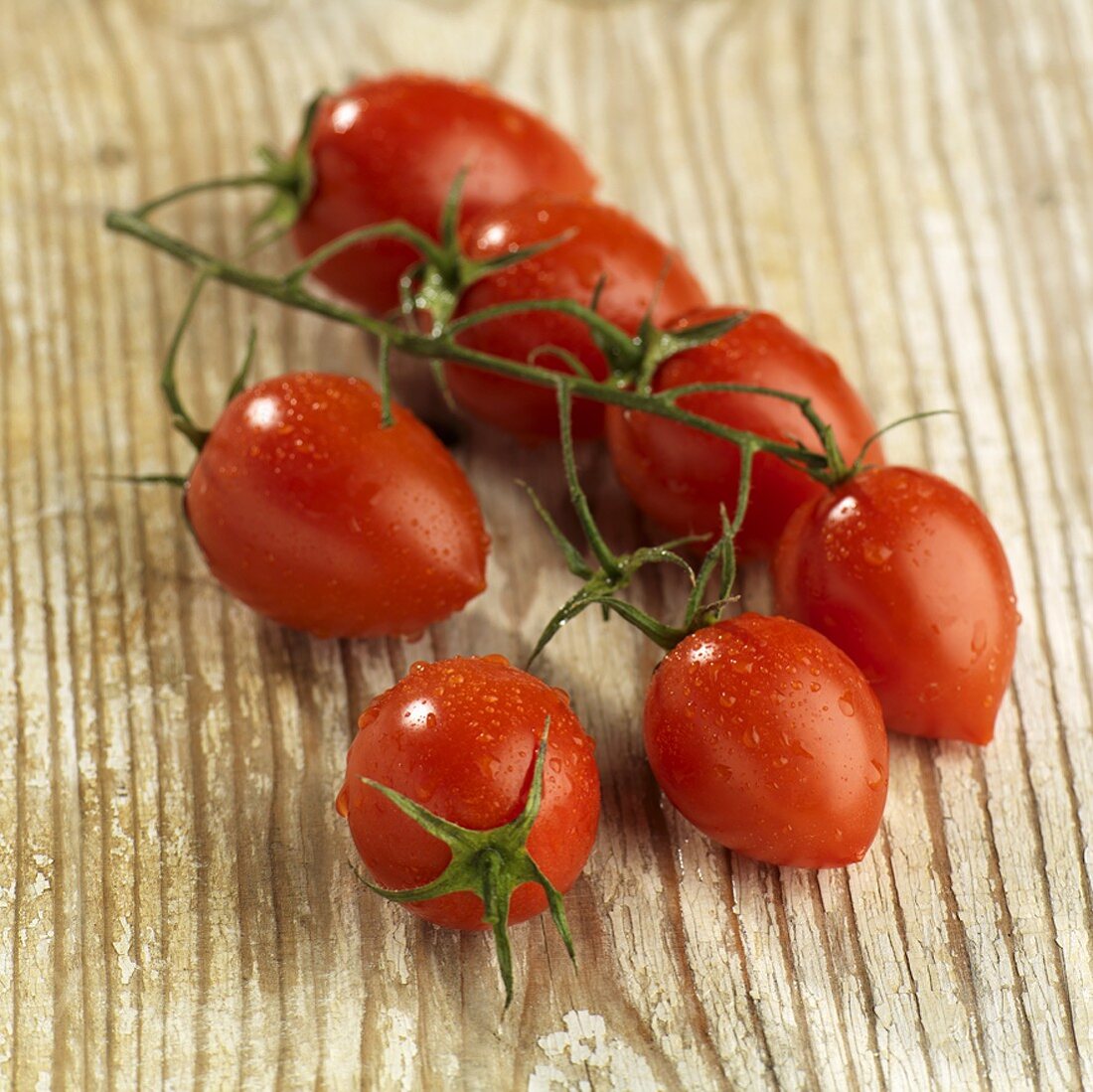 Plum tomatoes on the vine on wooden background