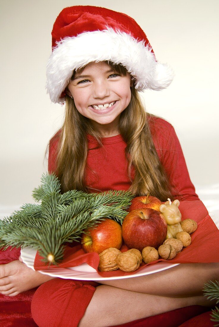 Girl holding plate of nuts and apples