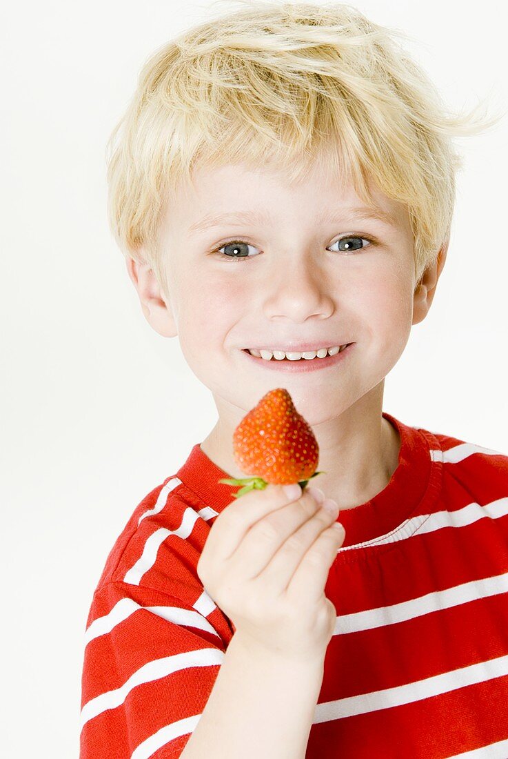Lächelnder Junge mit einer Erdbeere in der Hand