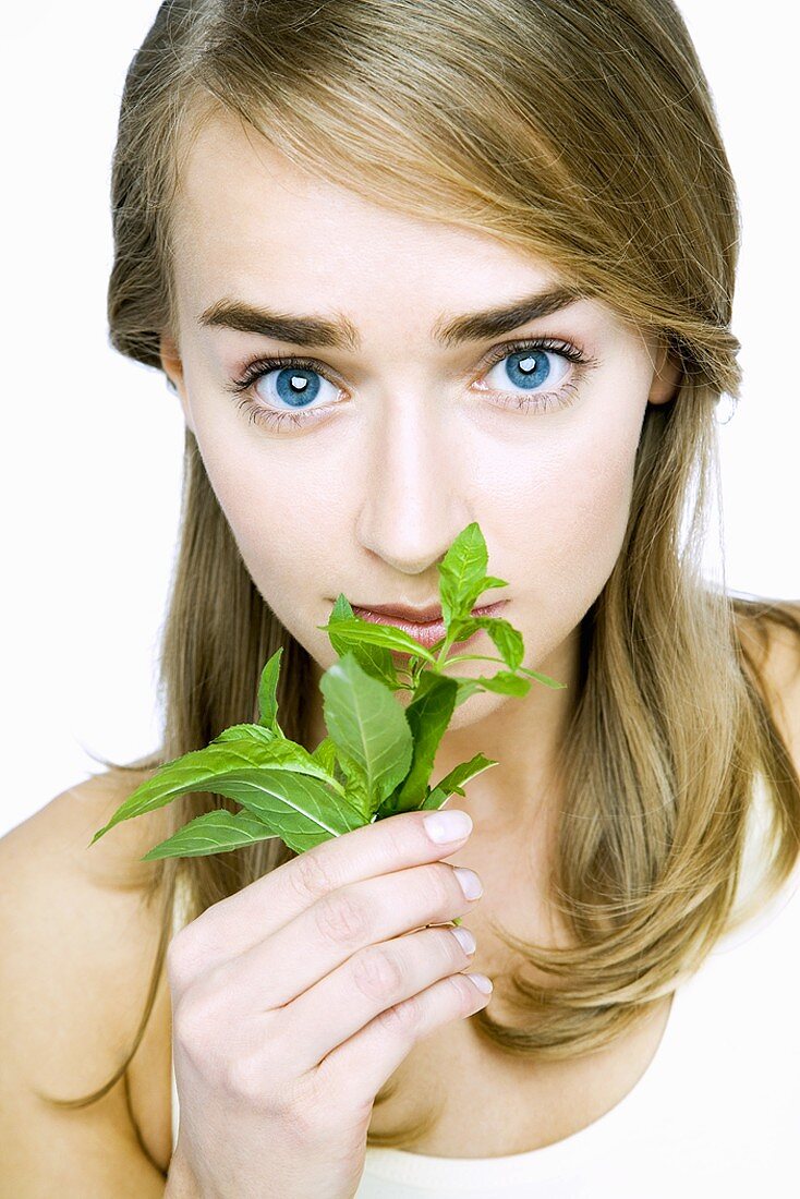 Young woman smelling fresh basil