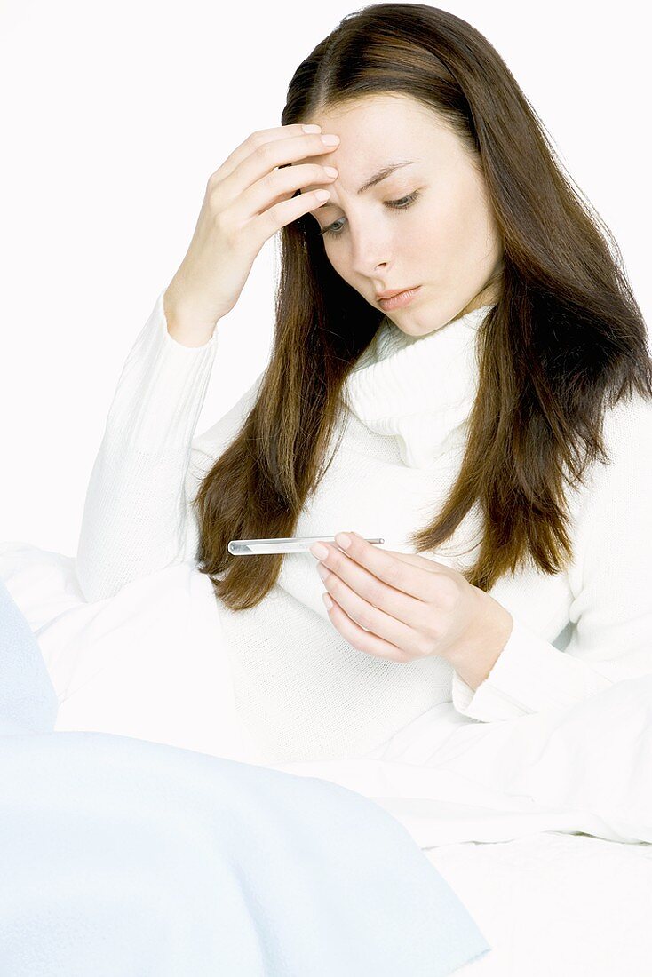 Junge Frau liest Fieberthermometer ab