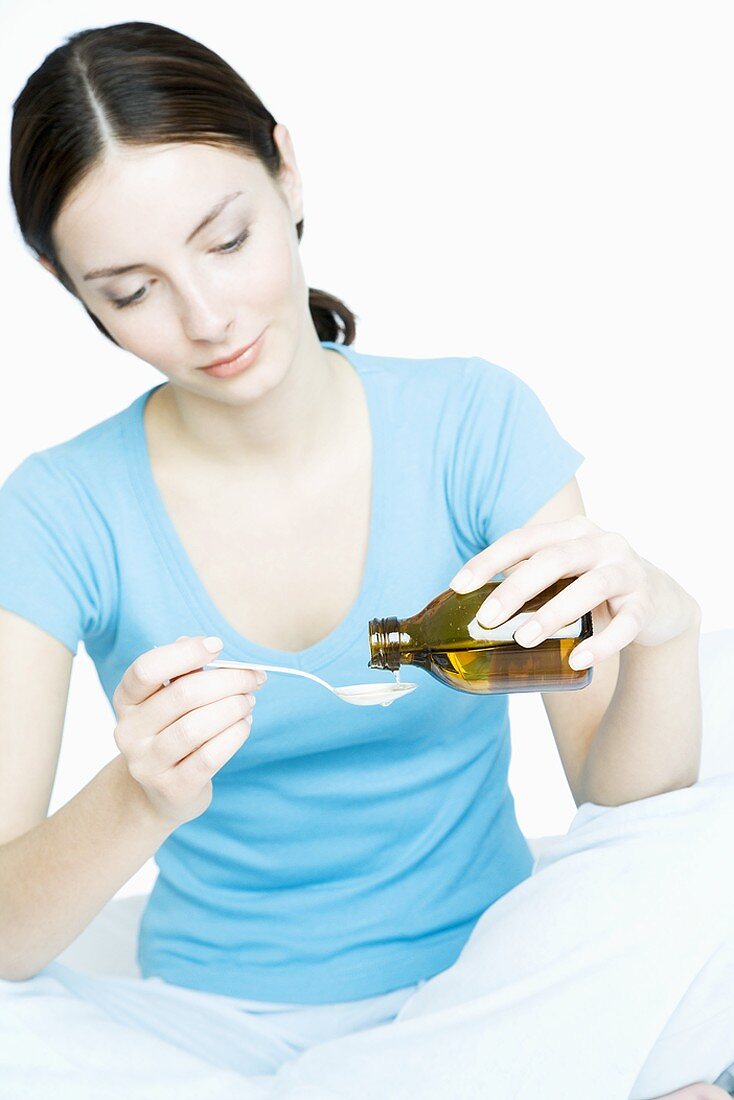 Young woman pouring medicine onto a spoon