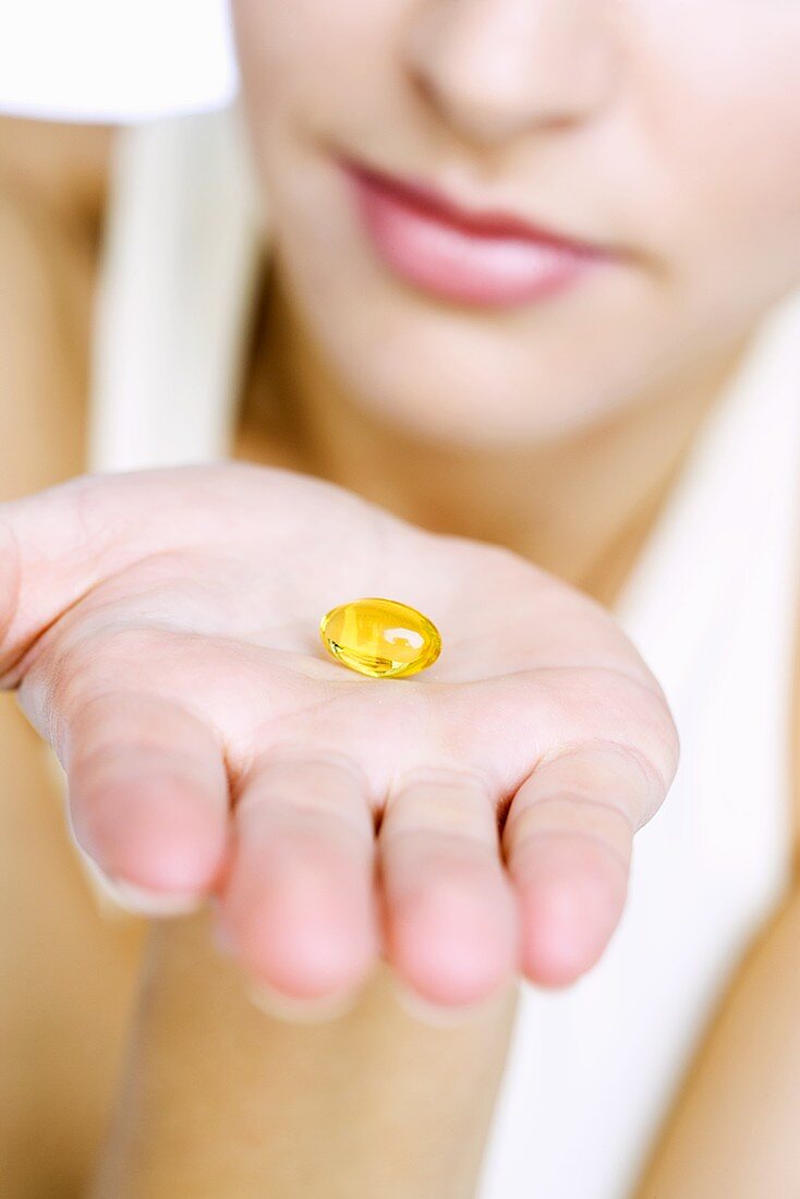 A vitamin capsule on someone's hand