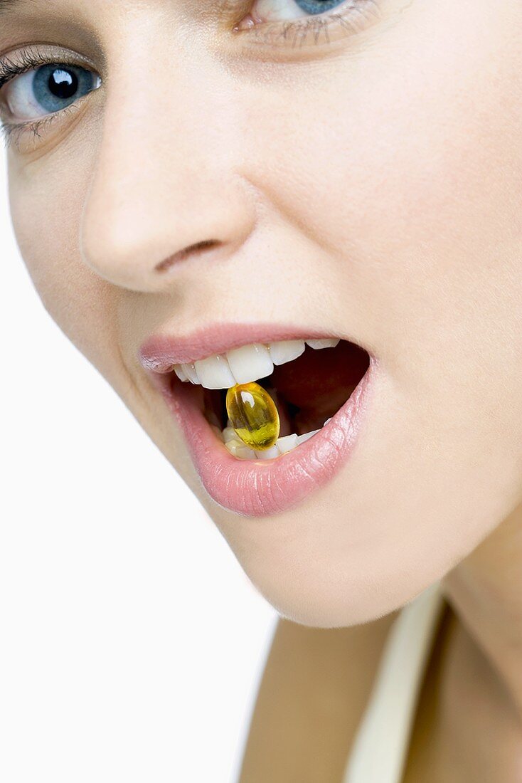 Frau mit Vitamintablette zwischen den Zähnen