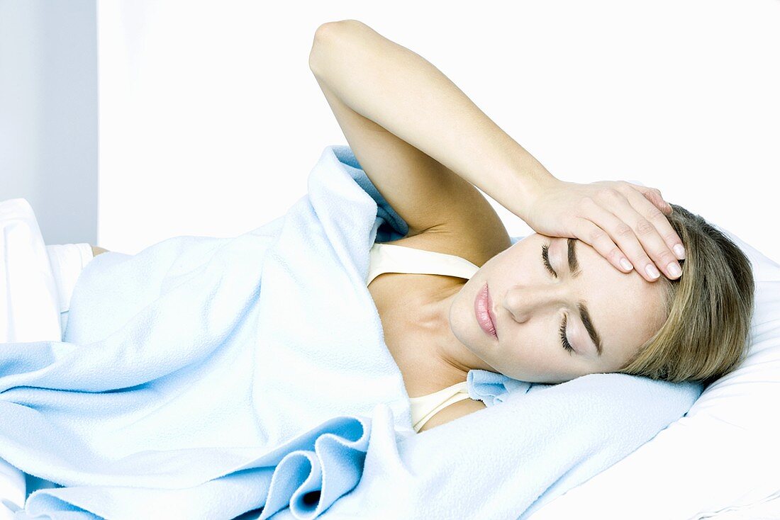 Woman lying in bed with headache