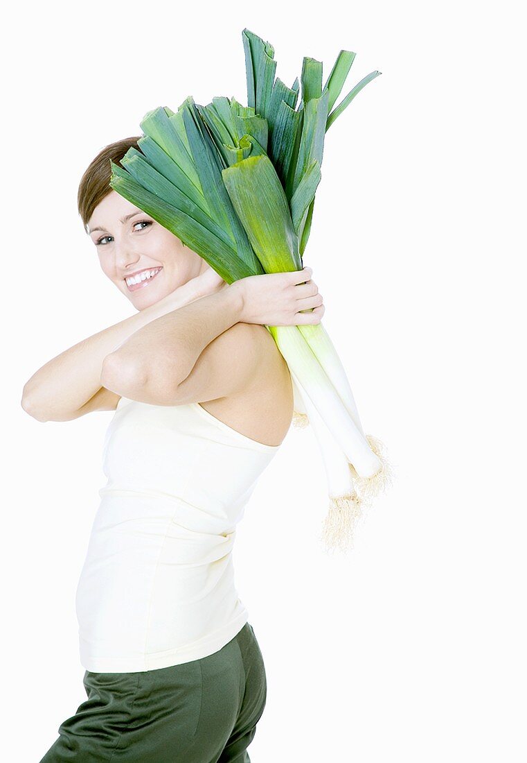 Young woman carrying fresh leeks over her shoulder