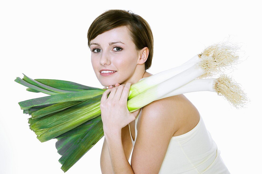 Young woman holding fresh leeks on her shoulder