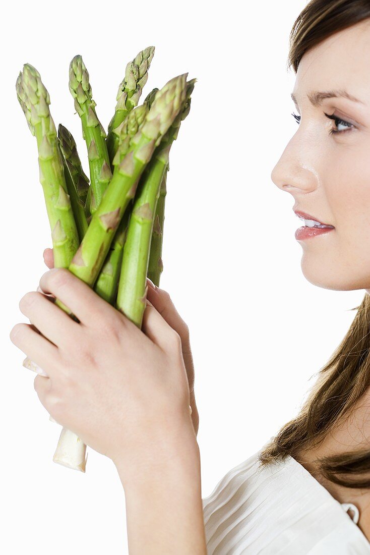 Young woman holding green asparagus in her hands