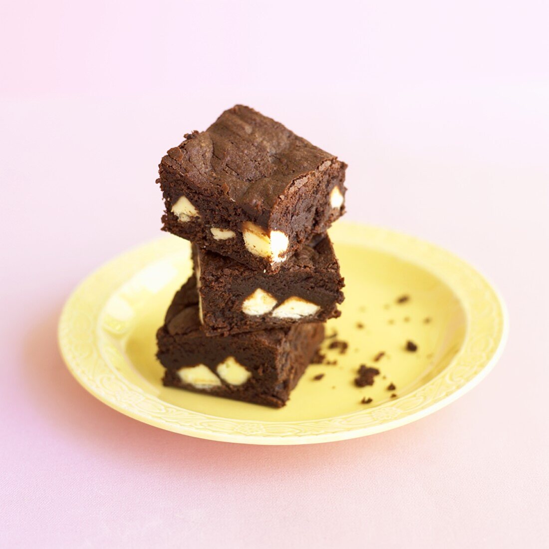A pile of three brownies on a plate