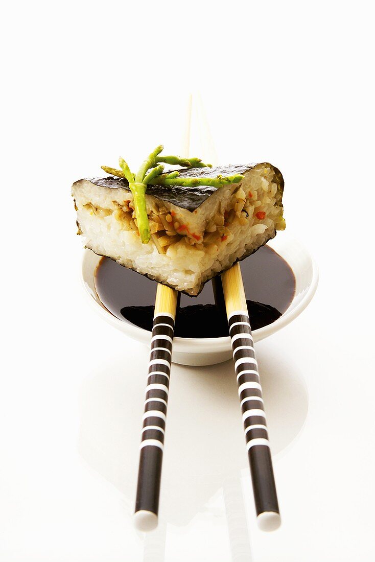 Sushi auf einem Schälchen Sojasauce mit Essstäbchen