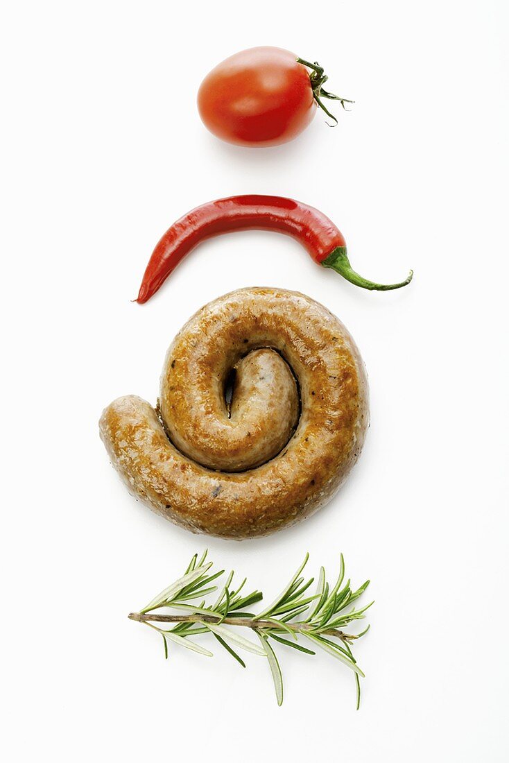 Eine Bratwurstschnecke zwischen Rosmarin, Chili & Tomate