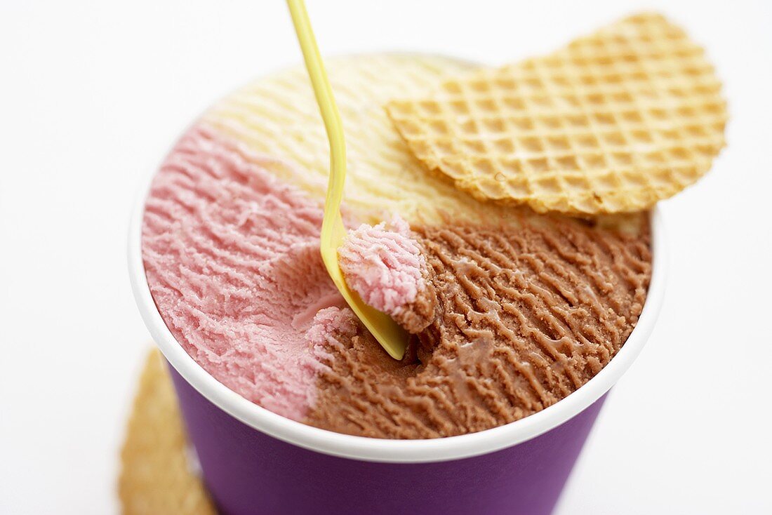 Neapolitan ice cream in tub with wafer
